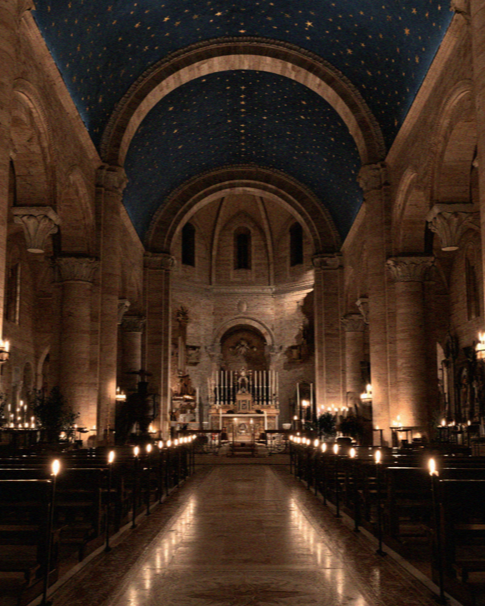 The dark Lower Basilica in Assisi with its deep blue vault of gold stars and rows of lit candles down the nave