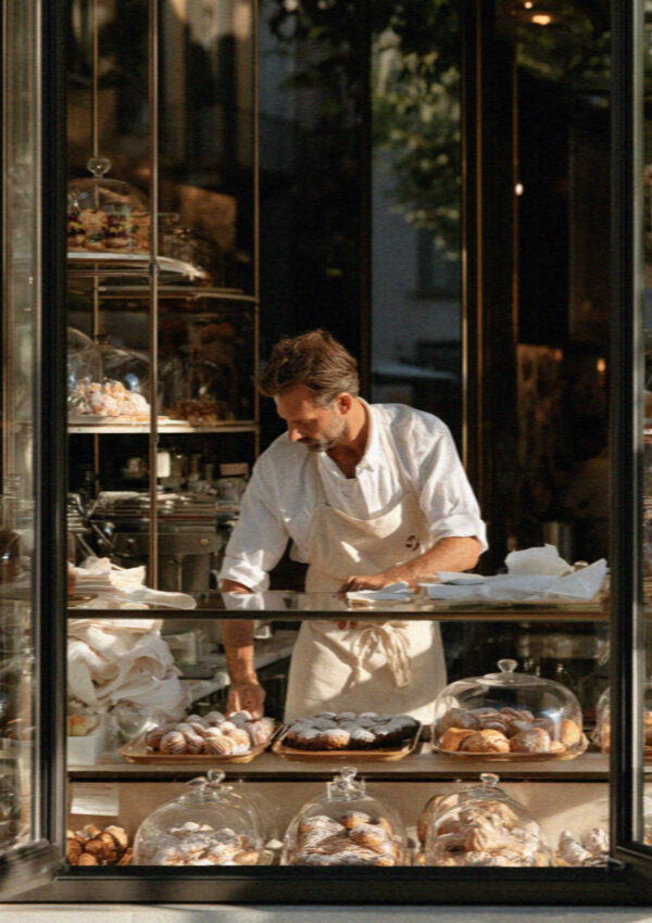 A pastry shopkeeper arranging trays in a Bergamo pasticceria window