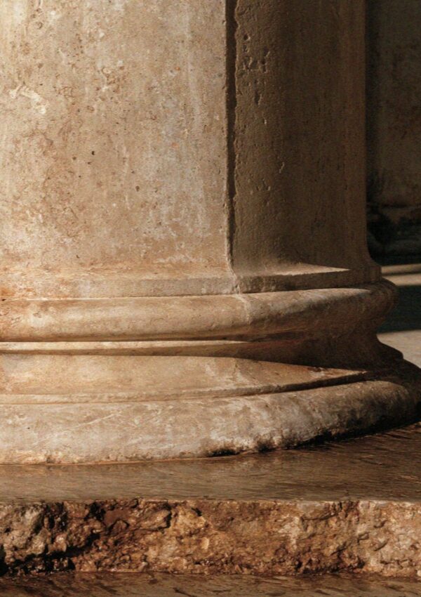 The worn stone base of a column in a Bologna arcade