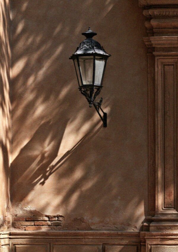 An old iron lamp on a Bologna wall in the morning sun