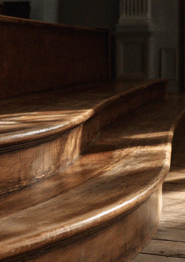 The worn edge of an old carved wooden bench in Bologna
