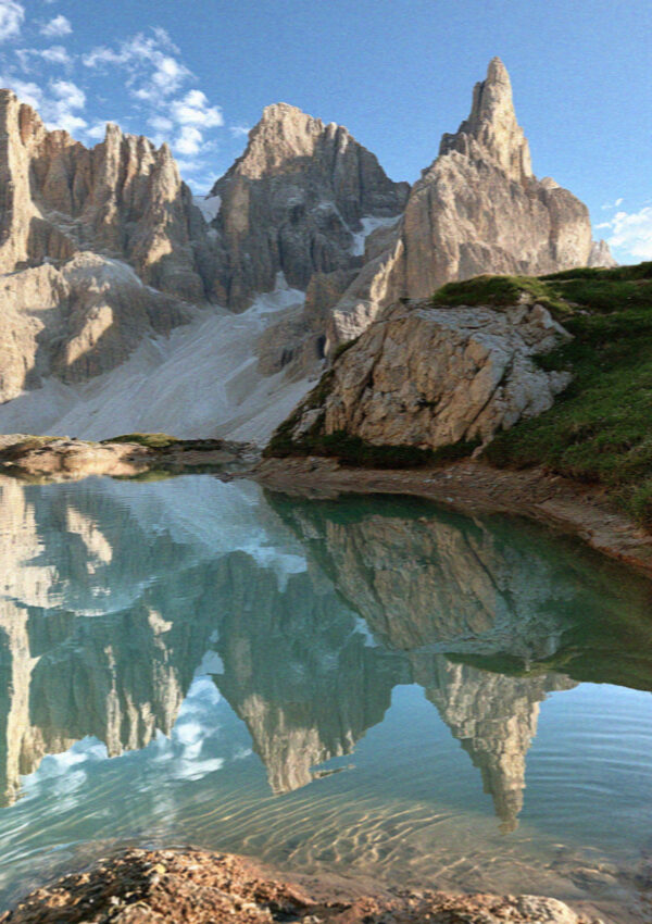 A still alpine tarn reflecting the peaks in the Dolomites