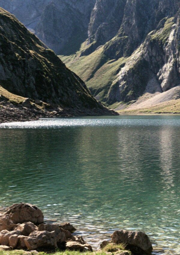 An emerald alpine lake below rock walls in the Dolomites