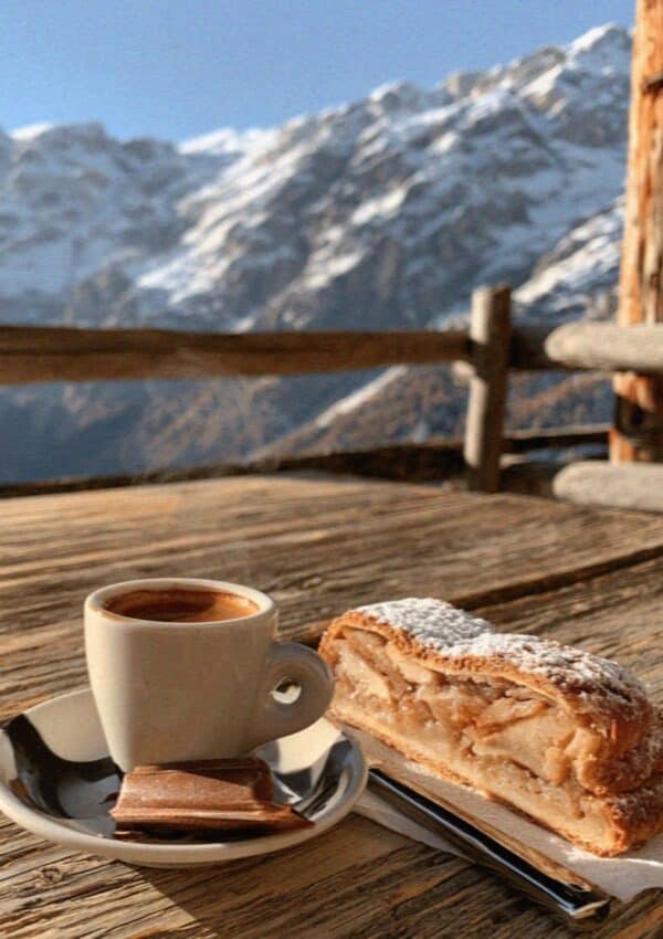 An espresso and apple strudel on a rustic Dolomites rifugio table