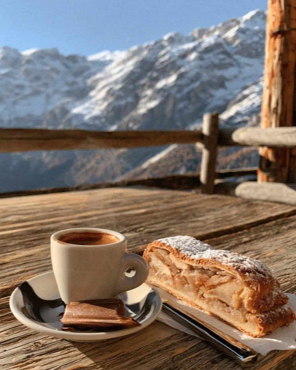 An espresso and apple strudel on a rustic Dolomites rifugio table