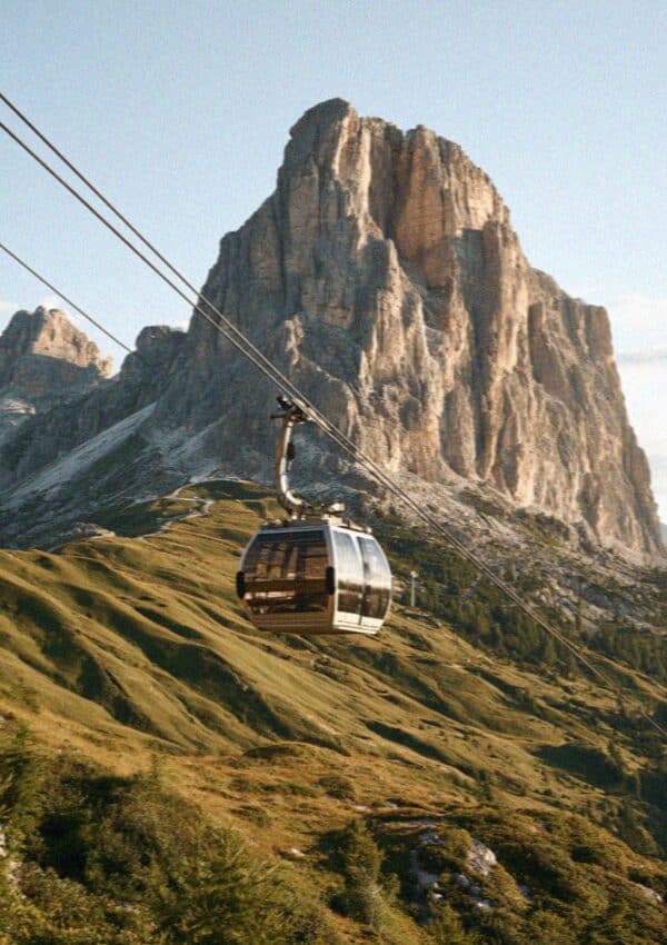 A gondola cable car climbing below a great Dolomite peak
