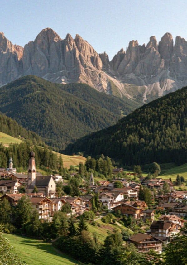 The pastel town of Ortisei and its church tower below the Odle peaks in Val Gardena, Dolomites
