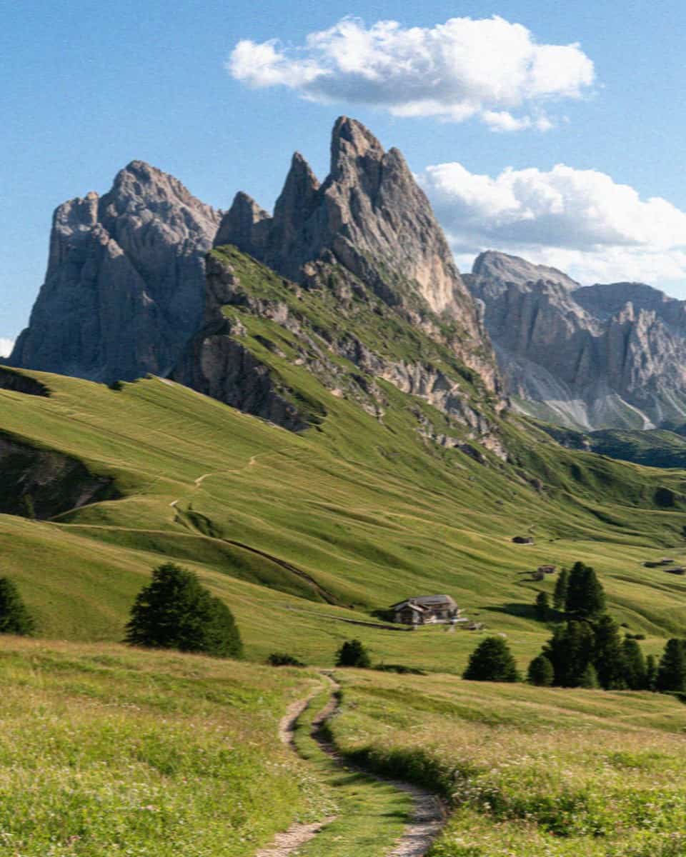A sweeping panorama of green meadows and pale Dolomite towers