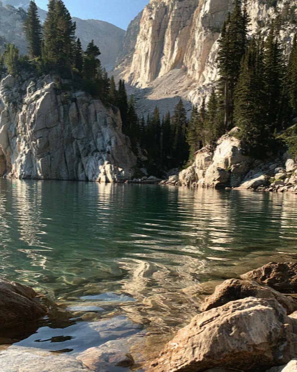 A turquoise mountain lake ringed by rock walls and pines in the Dolomites