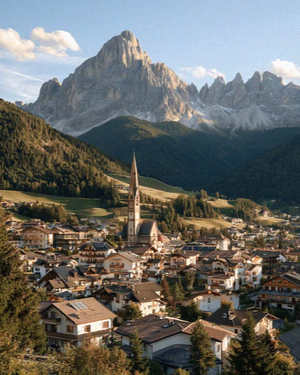 The rooftops and church spire of Ortisei clustered in Val Gardena below the Dolomite peaks