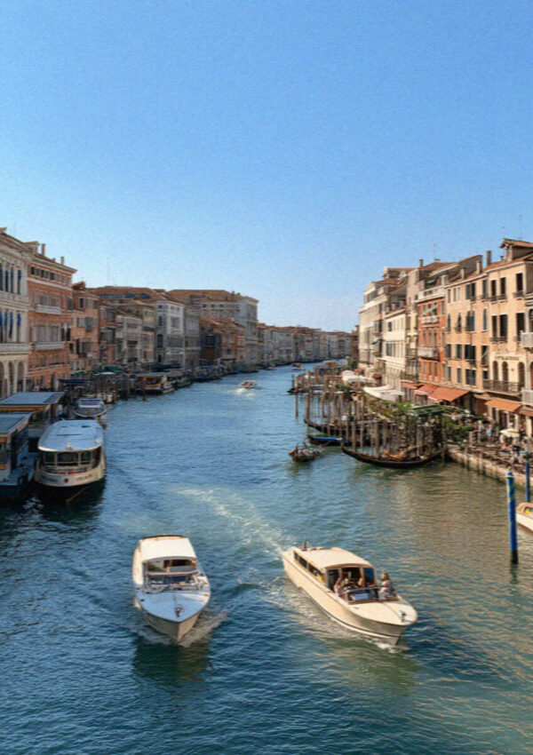 The Grand Canal of Venice lined with palazzi and busy with boats under bright light