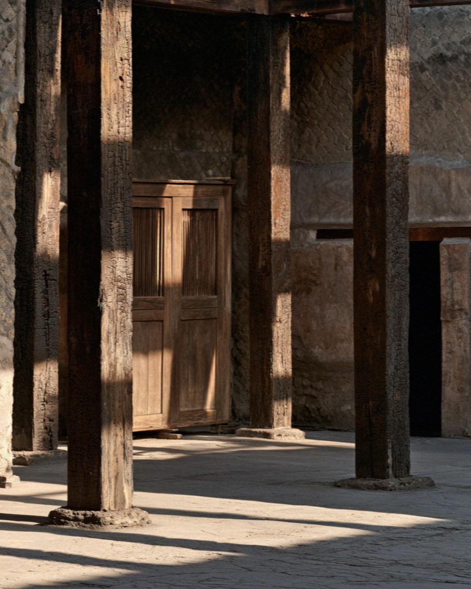 Blackened carbonised original wooden beams still in place above a doorway inside a house in Herculaneum, no people