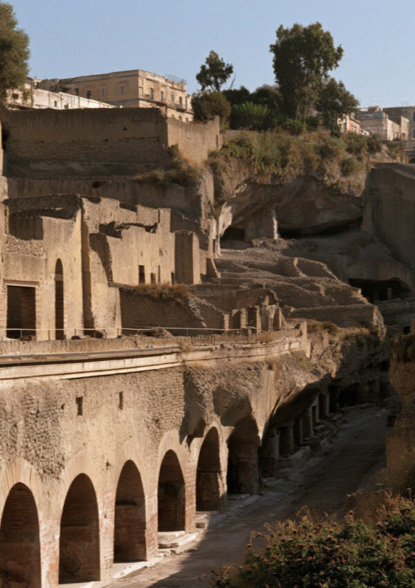 The excavated town of Herculaneum sunk far below the modern street level, arched chambers along the old shoreline, no people