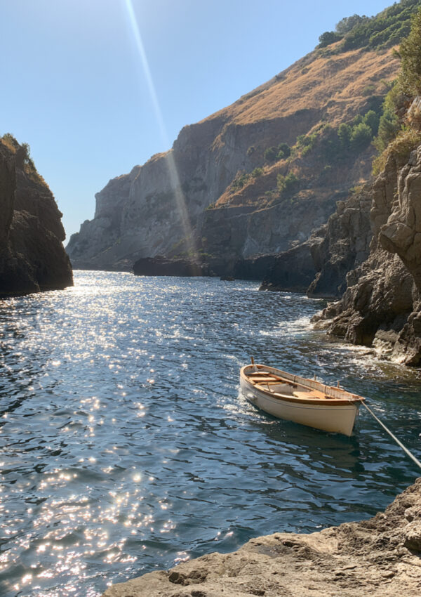A small boat in the cove below the cliffs at Sorgeto on Ischia
