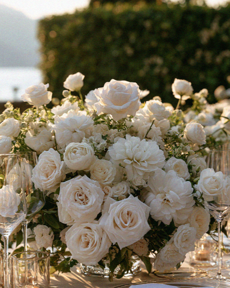 A lush white and green wedding floral arrangement on a lakeside table on Lake Como