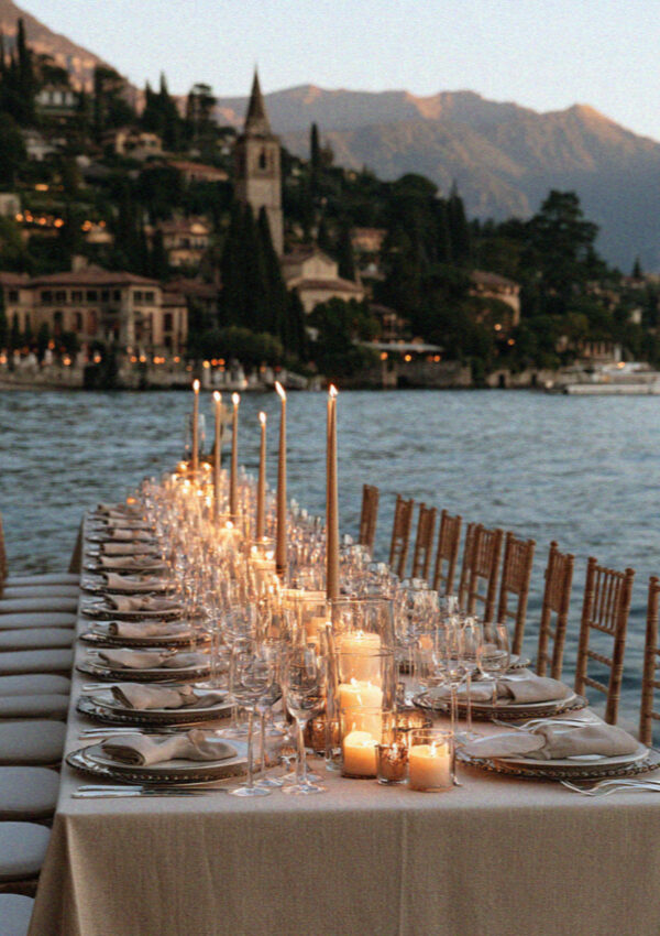 An elegant candlelit lakeside wedding table set for dinner on Lake Como