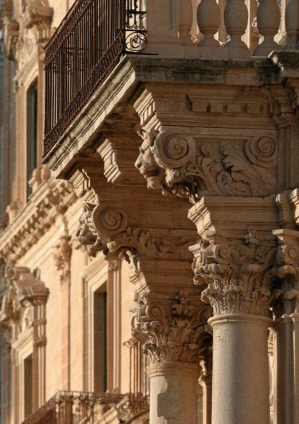 Carved stone corbels supporting a balcony on a limestone palazzo in Lecce