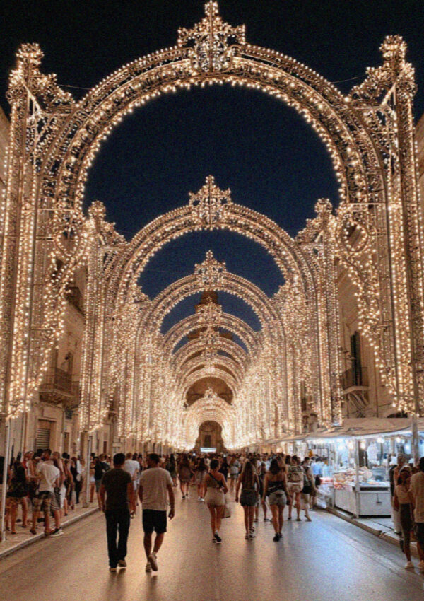 Arched festival light frames over a street in Lecce at night