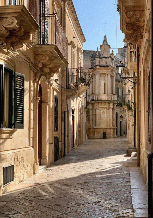 A narrow lane of golden limestone in the old town of Lecce, carved balconies on scrolled corbels