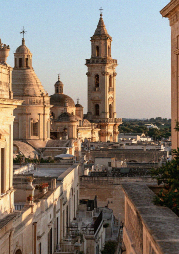 Golden stone rooftops, domes and a baroque bell tower in Lecce at dusk