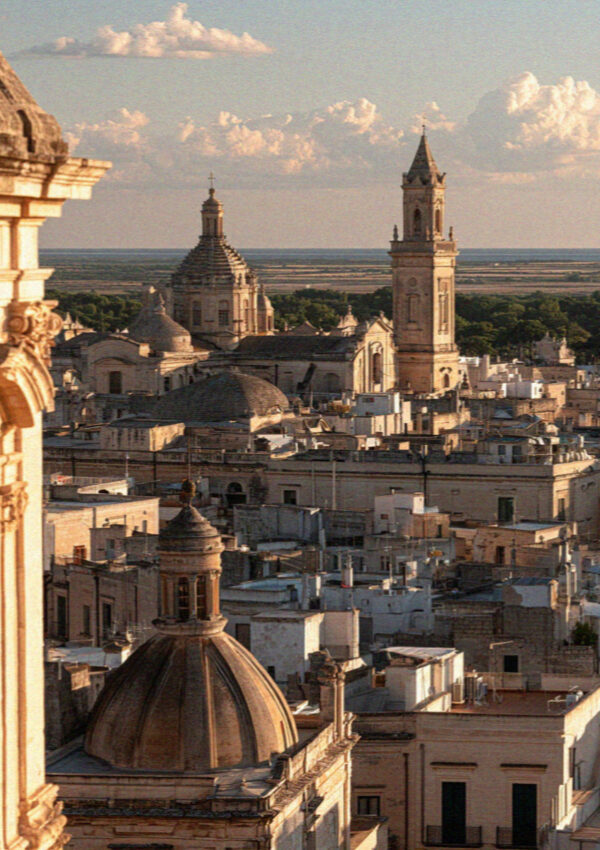 The rooftops and domes of Lecce from a bell tower, the Salento plain beyond