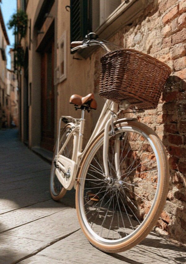 A vintage rental bicycle with a wicker basket against the brick wall of Lucca