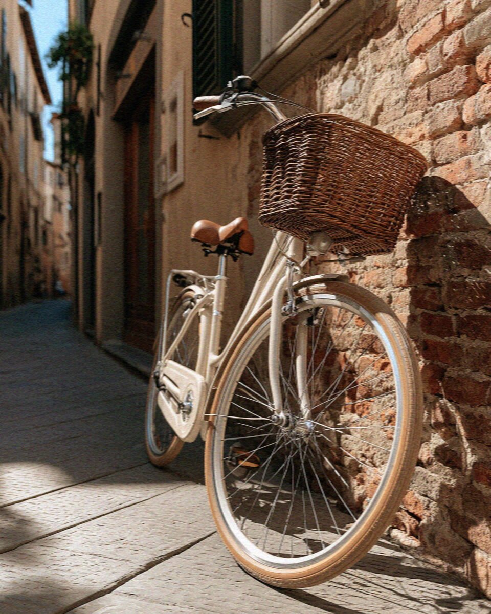 A vintage rental bicycle with a wicker basket against the brick wall of Lucca