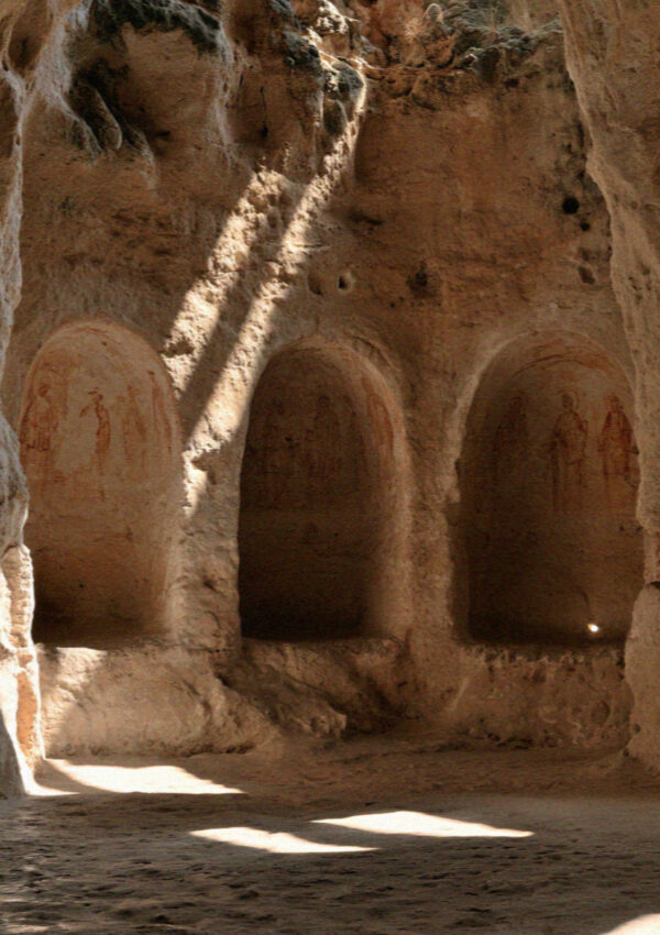 A rock-cut crypt near Matera, its three arched recesses painted with faded saints