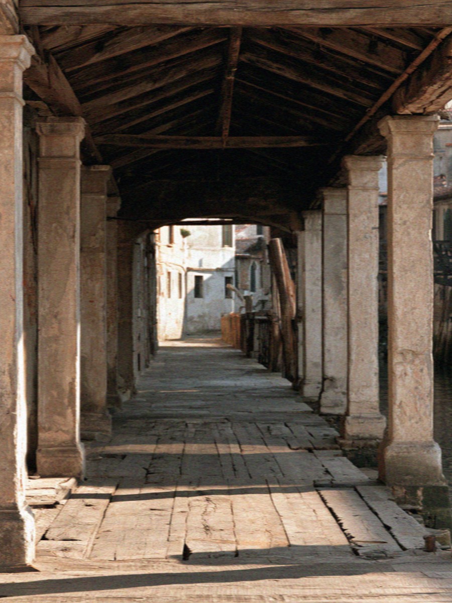 A shaded portico passage beside a Milan canal