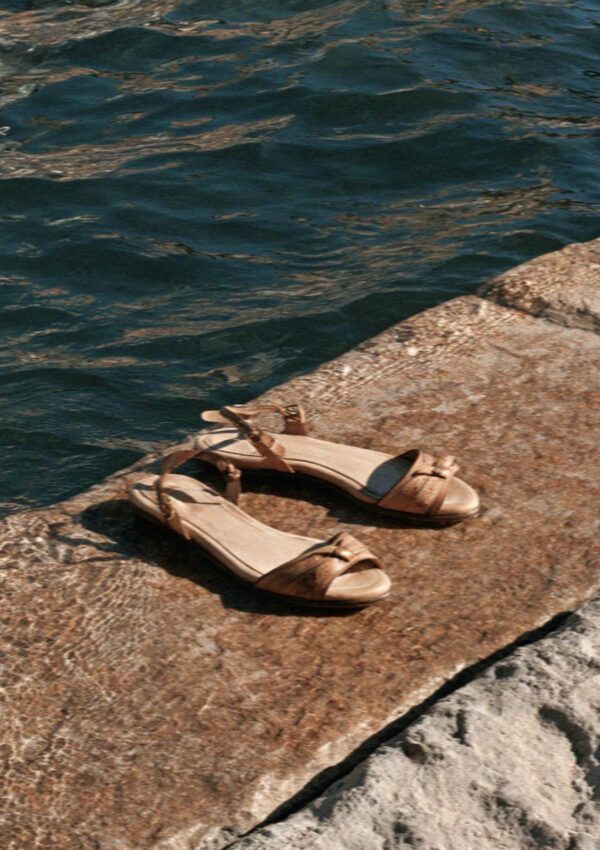 A pair of sandals left on warm canal stone in Milan