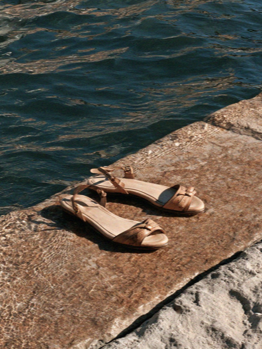 A pair of sandals left on warm canal stone in Milan