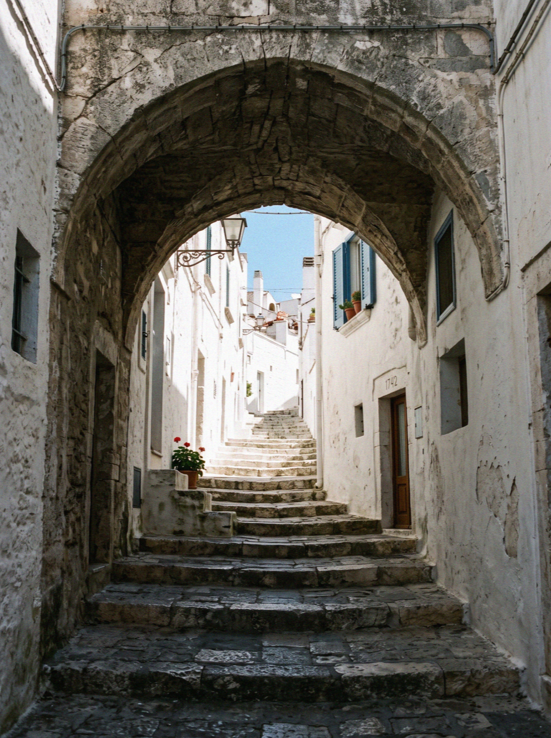 A vaulted stone archway over a narrow lime-washed lane in the old town of Ostuni