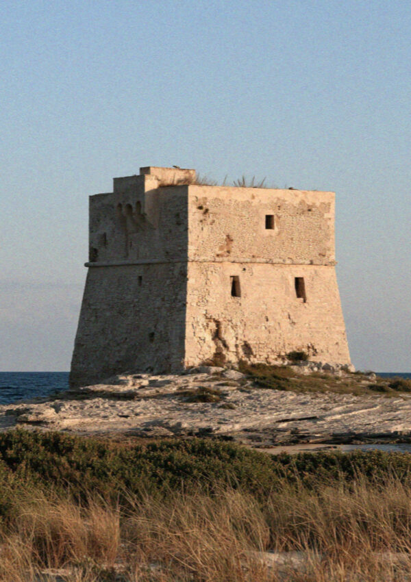 An old stone watchtower standing on the point above the coast near Ostuni