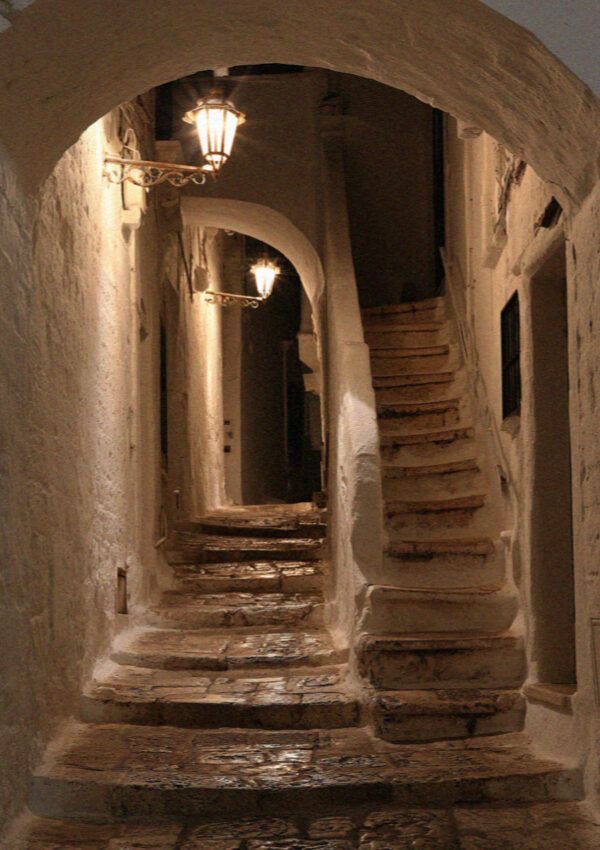 A vaulted whitewashed passage and worn stone steps in the old town of Ostuni