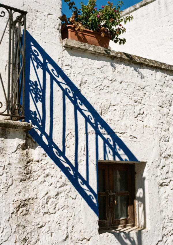 A thickly lime-washed white wall in Ostuni with a hard blue shadow falling across it
