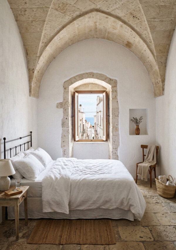 A whitewashed hotel room with a vaulted stone ceiling and deep set window in Ostuni
