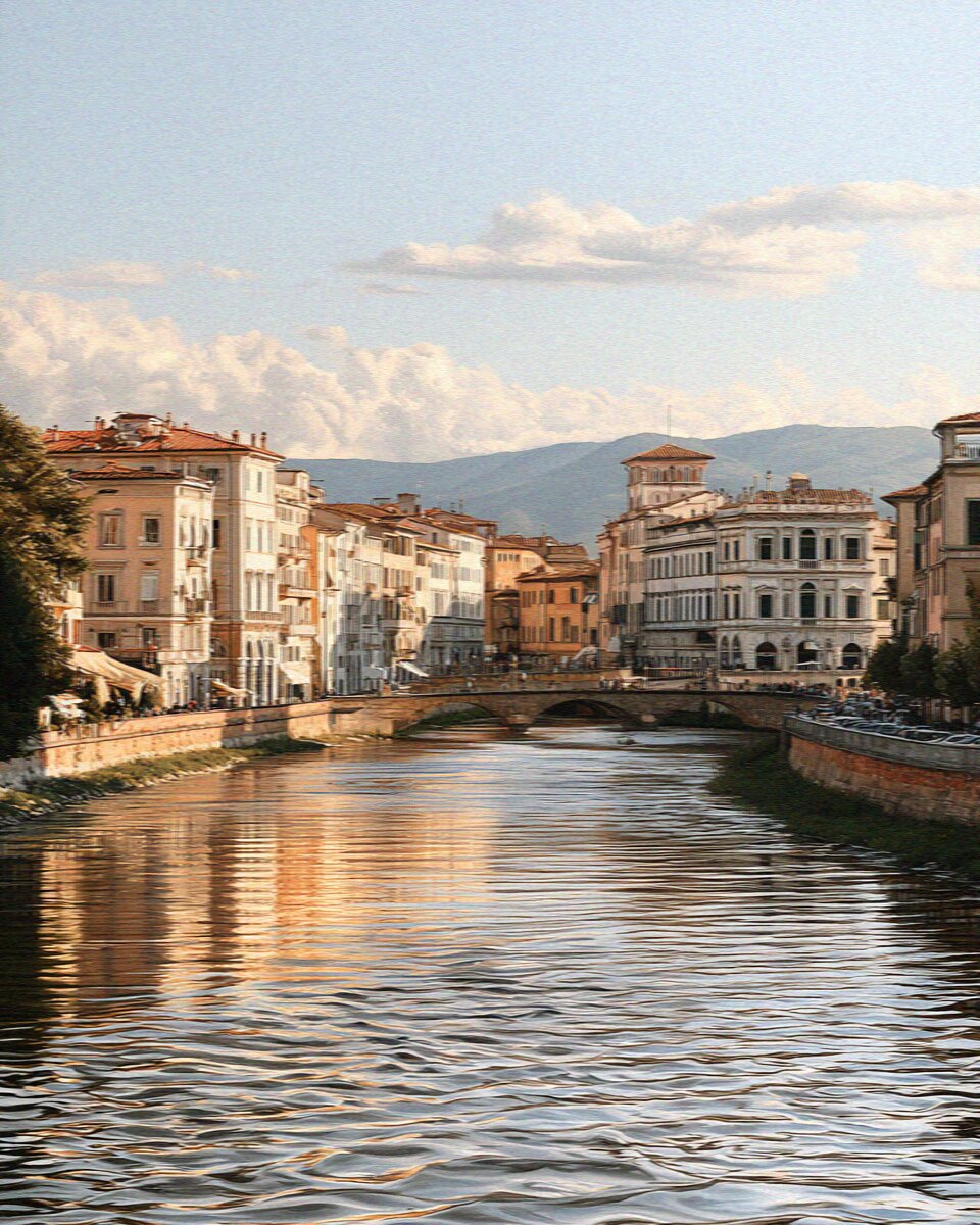 The Arno river through Pisa lined with pastel palazzi along the Lungarno