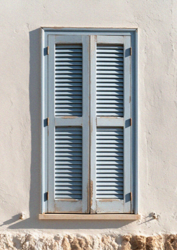 A blue shutter on a whitewashed wall in Polignano a Mare
