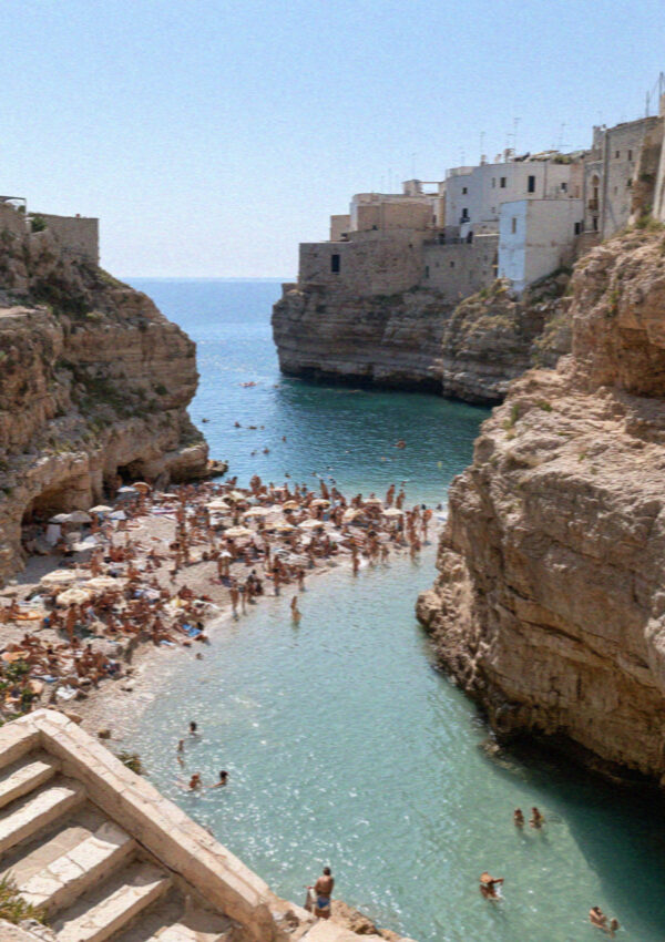 The crowded pebble cove at Polignano a Mare in the early afternoon