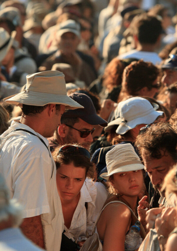 A queue of visitors with hats and water bottles waiting at the entrance gate of the archaeological site in Pompeii before opening