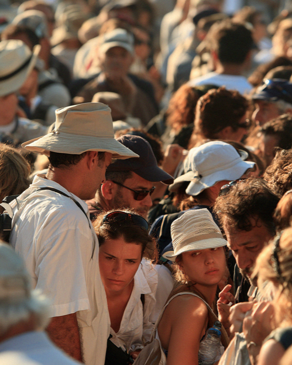 A queue of visitors with hats and water bottles waiting at the entrance gate of the archaeological site in Pompeii before opening