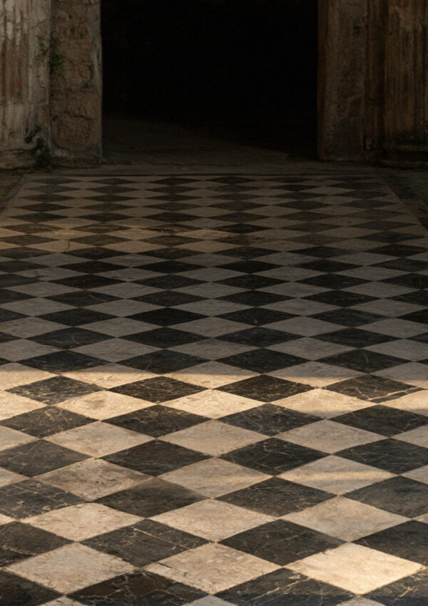 A black and white geometric mosaic floor in a house in Pompeii in soft indirect light, no people