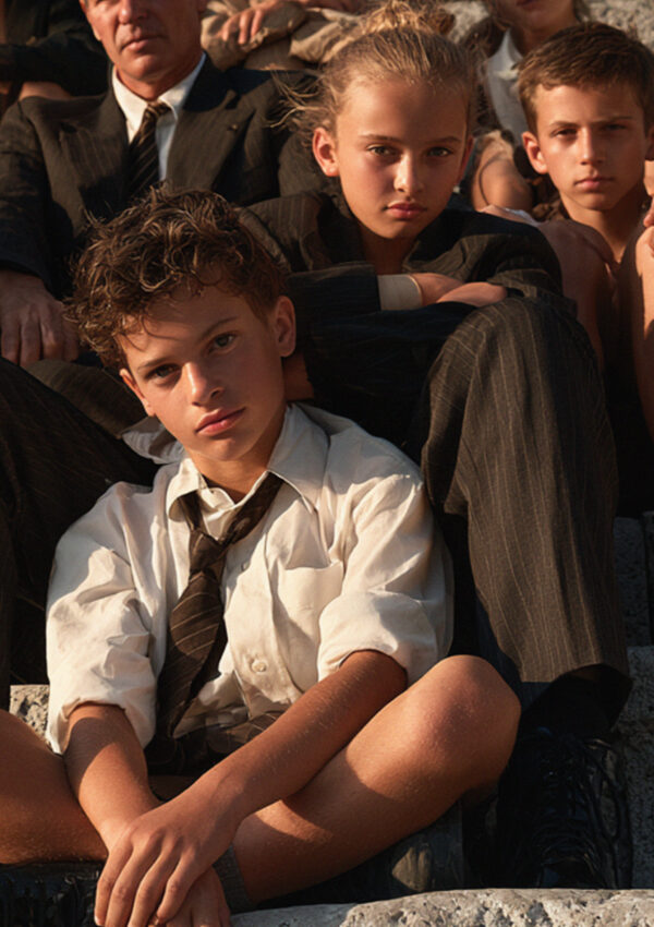 A group of Italian schoolchildren sitting with their teacher on ancient stone steps in Pompeii in late morning light