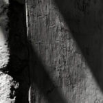 Close-up of scratched ancient lettering in a stucco wall in Pompeii with raking light across the surface