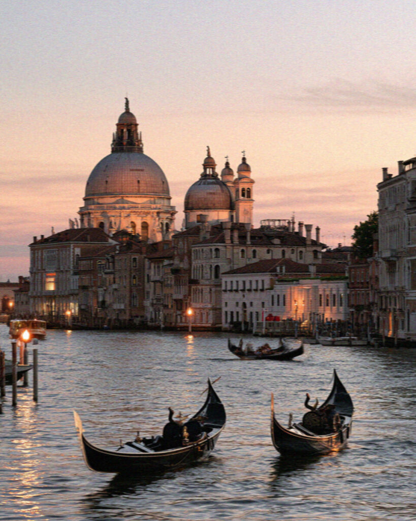 The domes of Santa Maria della Salute glowing at dusk with gondolas on the darkening Grand Canal
