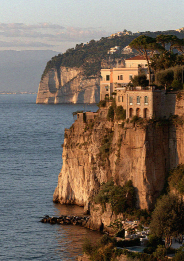 The cliffs below Sorrento turned warm apricot in low evening light above a calm sea