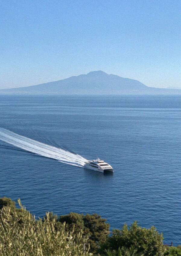 A ferry crossing the bay off Sorrento leaving a long white wake, with Vesuvius hazy on the far shore
