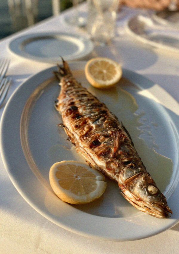 A plate of simply grilled fish with cut lemon on a white cloth in Sorrento