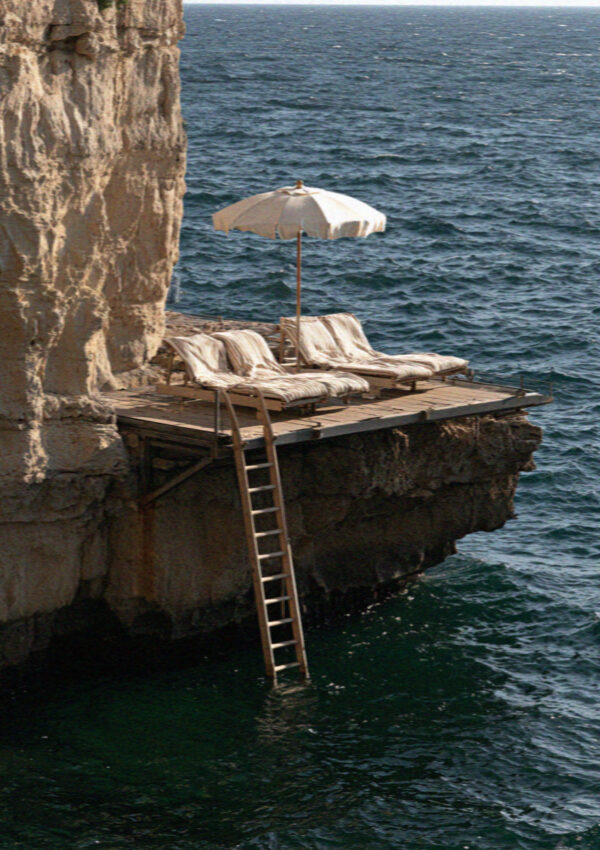 An empty bathing platform with a ladder down into clear water below the cliffs at Sorrento