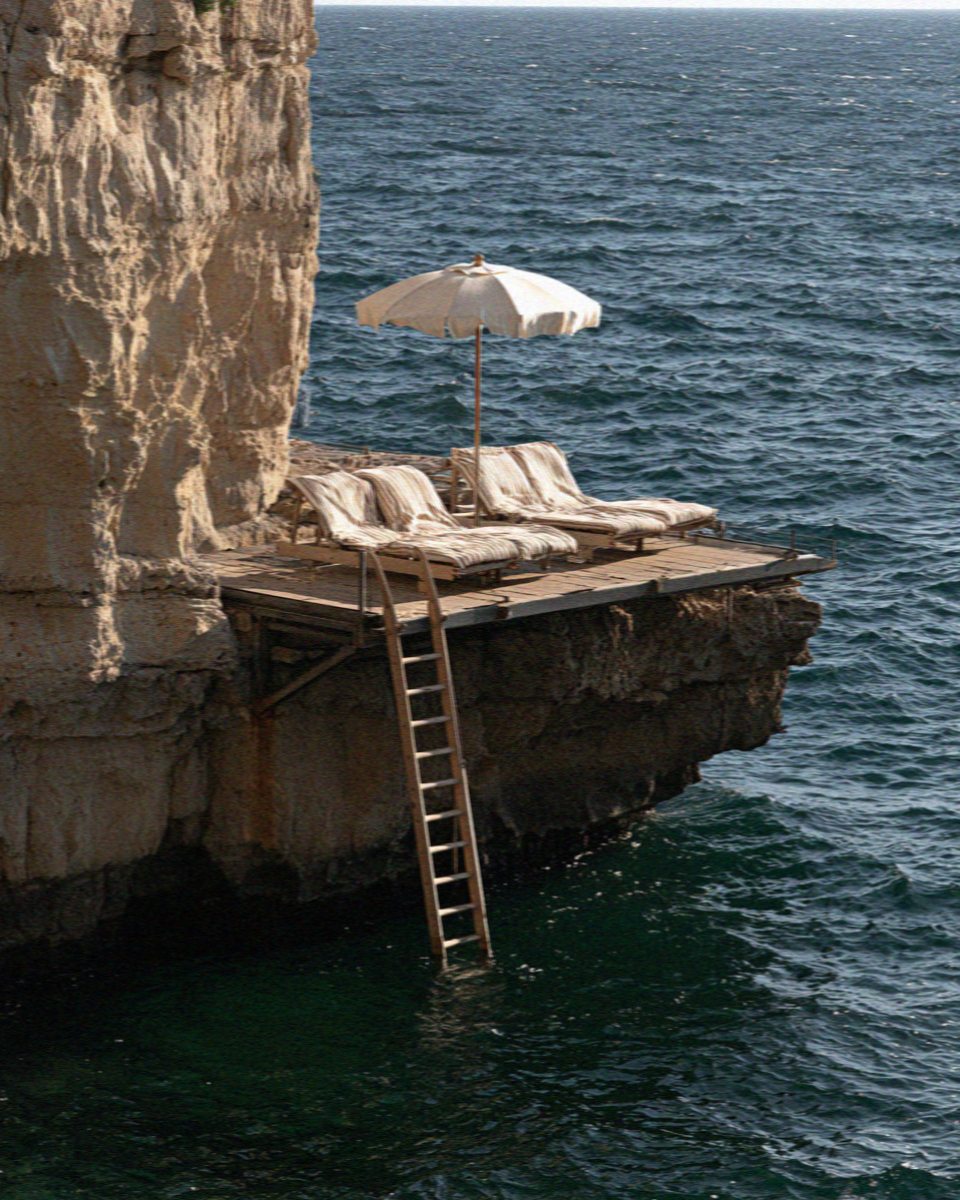 An empty bathing platform with a ladder down into clear water below the cliffs at Sorrento